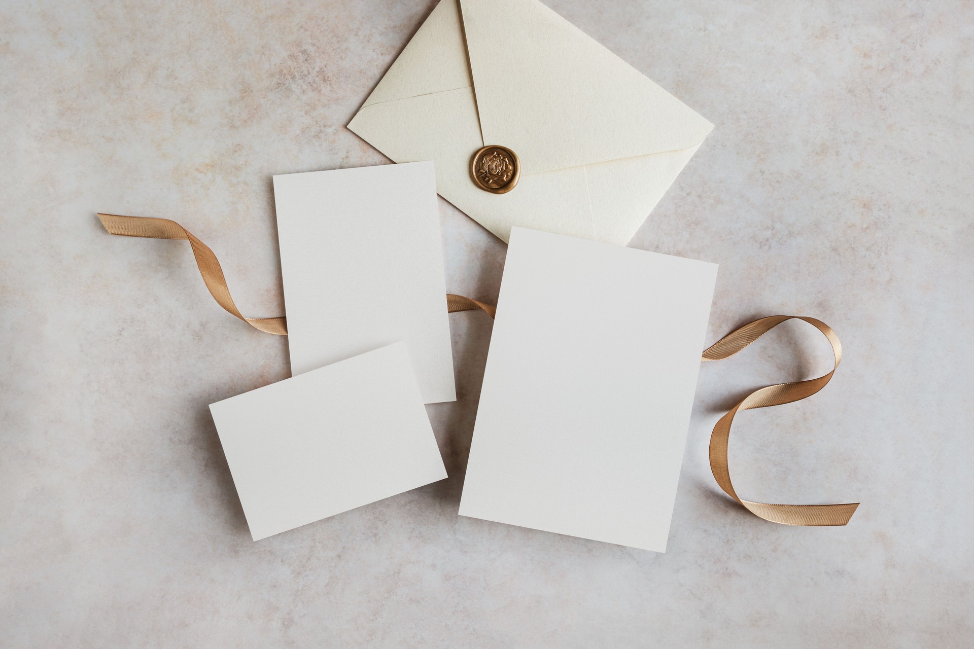 Set of blank invitation cards and envelope mockup with gold ribbon top view